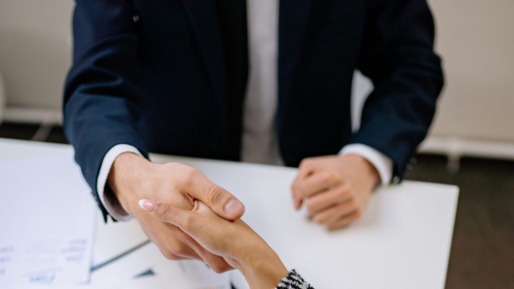 Handshake over documents at a conference table — collaborative divorce attorneys in White Plains and Garden City, NY